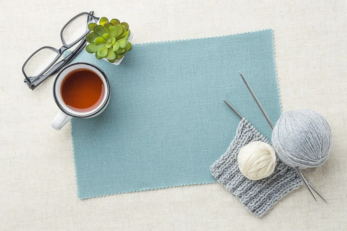 Draufsicht auf ein Häkelset mit Garn und Tee.