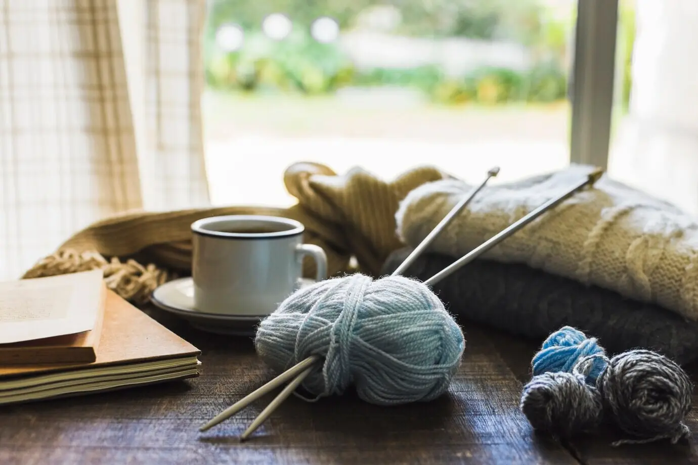 Strickzubehör und Getränk in der Nähe eines Fensters